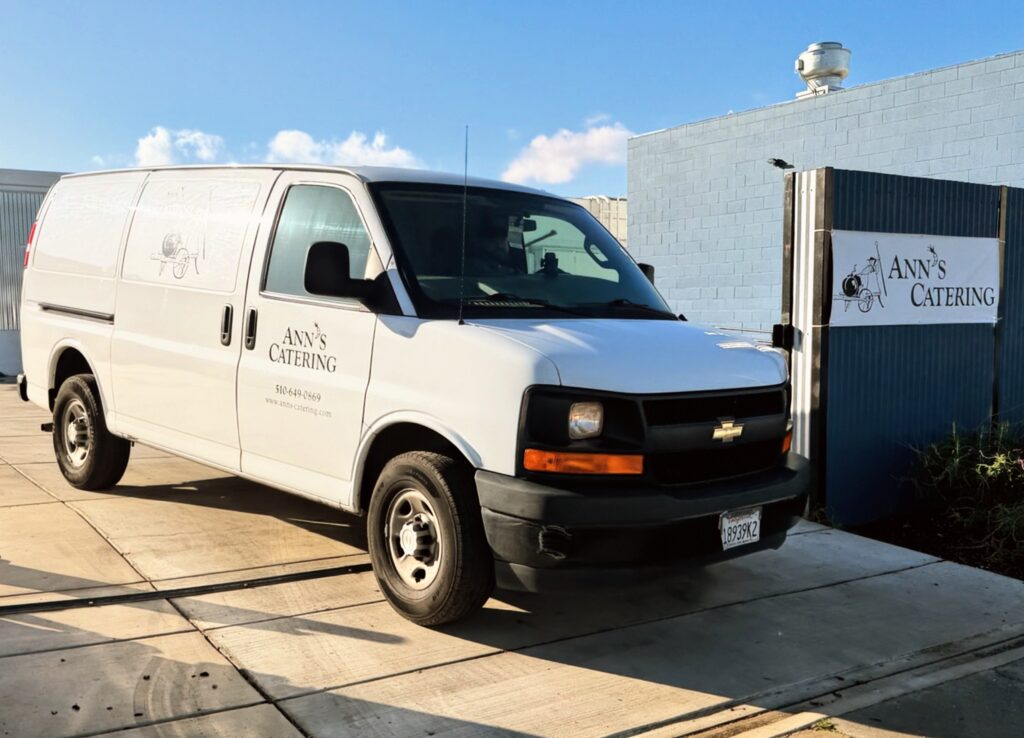Ann's catering van driving out of our parking lot next to an Ann's catering sign